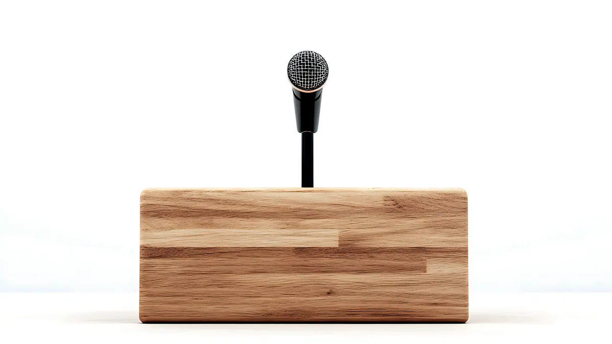 Un micfono de pie sobre un atril de madera en un auditorio con sillas vacias.
