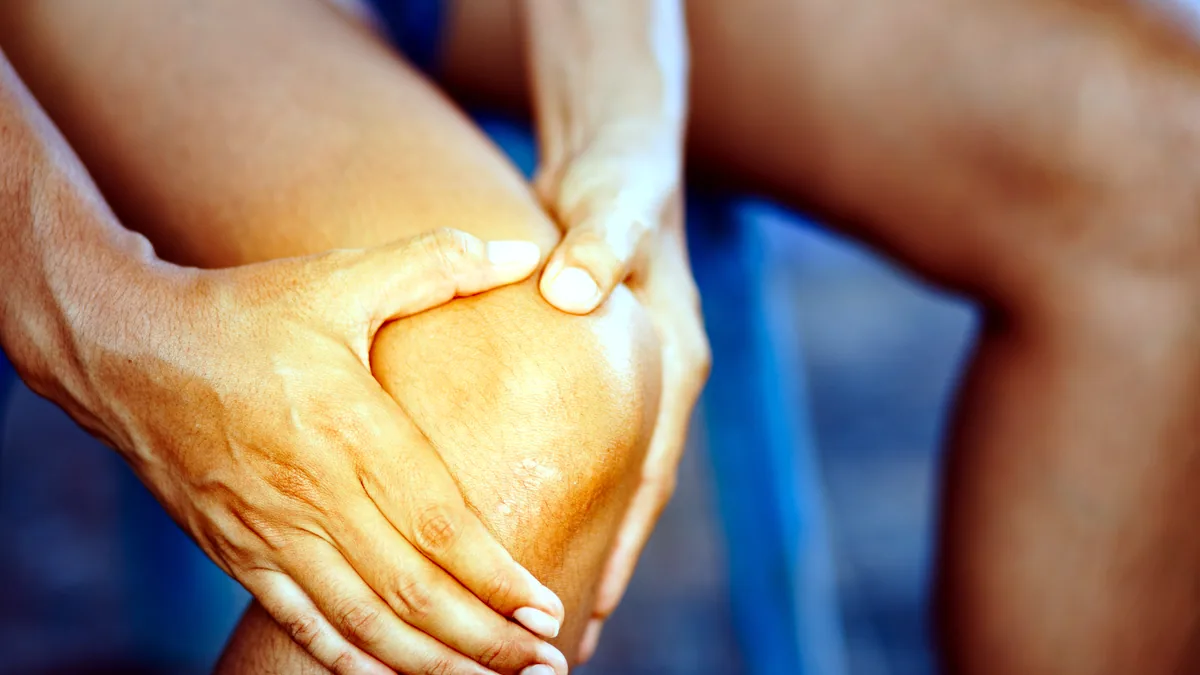 La articulacion de una rodilla humana vista en primer plano sobre un fondo neutro.